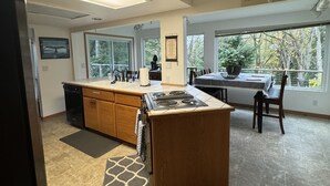 A spacious kitchen with a central island, a dining area with a table and chairs, and large windows offering a view of the outdoors. - Upper Level with a view close to Boeing (everett)