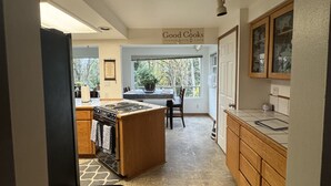 A kitchen with a central island, wooden cabinets, a stove, and a dining area with a table and chairs. - Upper Level with a view close to Boeing (everett)