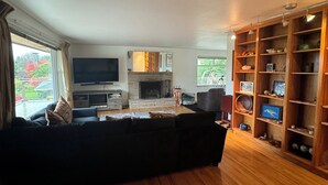 A living room with a black sofa, a fireplace, a TV, and a wooden bookshelf. - Upper Level with a view close to Boeing (everett)