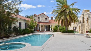 A pool area with a stone building, palm trees, and a clear sky.