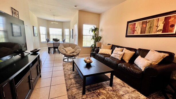 A living room with a sofa, coffee table, TV, and a dining area with chairs and a table.
