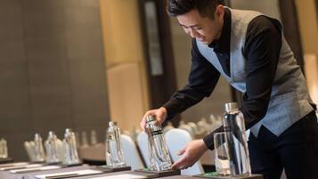 A person arranging glass bottles on a table in a hotel setting.