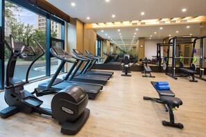 A gym with treadmills, weight machines, and a bench. - Doubletree by Hilton Qingdao Oriental Movie Metrop (Qingdao)