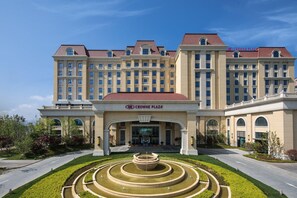 A large hotel with a central entrance, a fountain in front, and a clear sky. - Doubletree by Hilton Qingdao Oriental Movie Metrop (Qingdao)