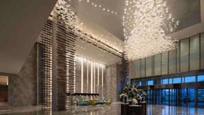 A spacious lobby with a high ceiling, a seating area with sofas, and a large decorative light fixture. - Doubletree by Hilton Qingdao Oriental Movie Metrop (Qingdao)