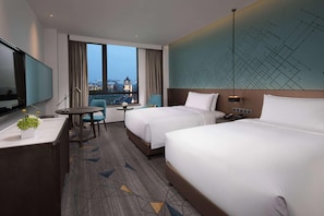 A hotel room with two beds, a desk, a chair, a TV, and a view of the cityscape. - Doubletree by Hilton Qingdao Oriental Movie Metrop (Qingdao)