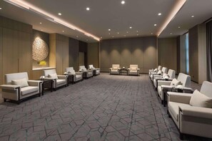 Un salón de conferencias con una larga mesa, varias sillas y una alfombra estampada.