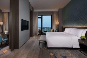 Una habitación de hotel con una cama grande, televisión, balcón y vistas a la ciudad.