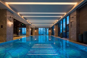 A modern indoor swimming pool with a clear view of the sky through large windows. - Doubletree by Hilton Qingdao Oriental Movie Metrop (Qingdao)