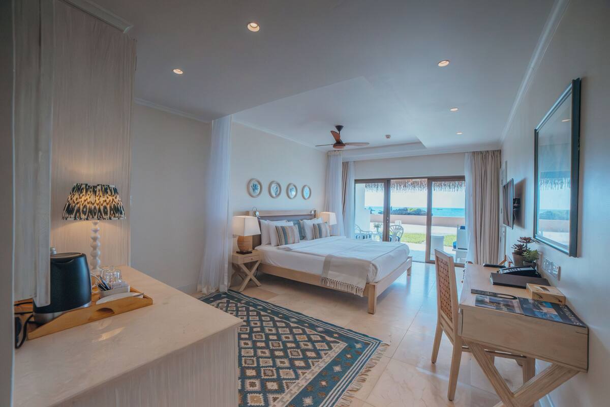 Habitación de hotel con cama, escritorio, silla y vista al exterior.