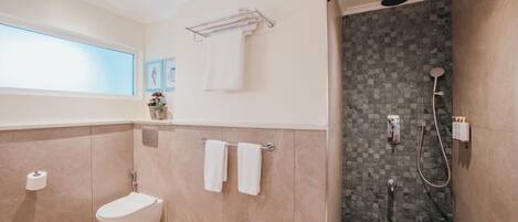 A modern bathroom with a freestanding bathtub, a shower with a rain showerhead, and a toilet.