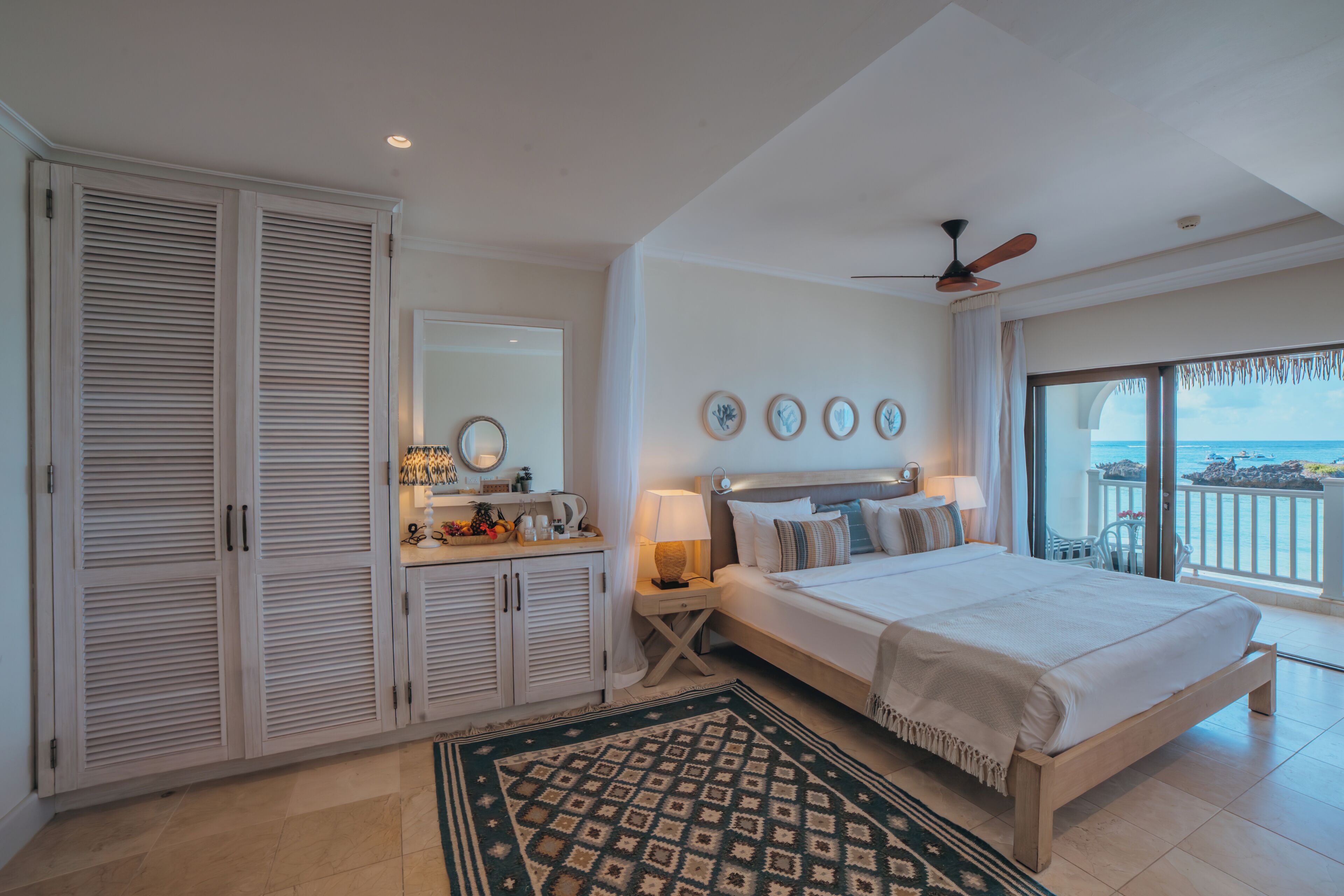 Une chambre à coucher avec un lit, une table de chevet, un miroir, une armoire et une vue sur la mer.