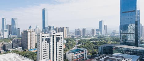 Un paysage urbain avec des immeubles modernes de grande hauteur, un mélange de bâtiments commerciaux et résidentiels, et un ciel dégagé.