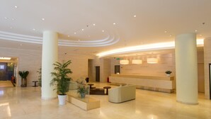 A modern lobby with a reception desk, seating areas, and potted plants. - JI Hotel (Shenzhen)
