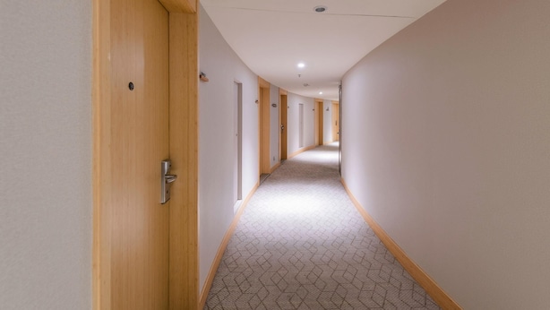 A long, narrow hallway with wooden doors on one side and a patterned carpet. - JI Hotel (Shenzhen)