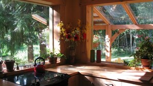 Eine Holzhütte mit einer Küche, einem großen Fenster, Holzschränken und einem Herd.