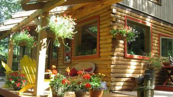 Relax on the porch with a comfortable Adirondack chair amidst lush potted plants.