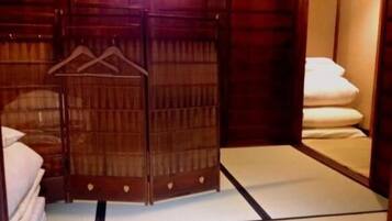 A traditional Japanese-style room with tatami flooring, a shoji screen door, and a bed with white bedding.