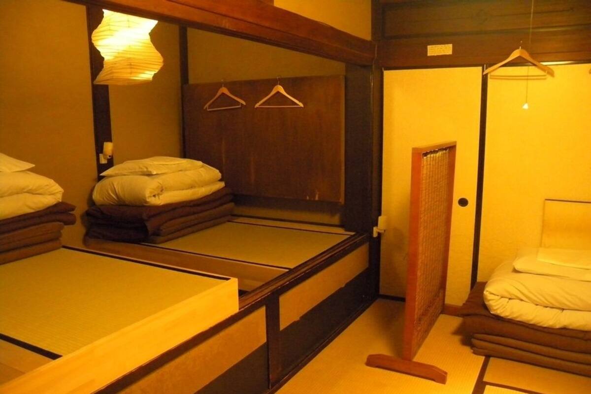 Een traditionele Japanse kamer met tatami vloerbedekking, een laag houten bed en een schuifdeur.