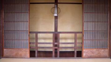Una habitación tradicional japonesa con suelo de tatami, puertas correderas y una lámpara colgante.