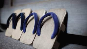 A row of wooden flip-flops with blue straps on a wooden bench.