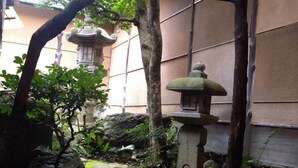 Un jardín japonés tradicional con faroles de piedra, un puente de piedra y abundante vegetación.