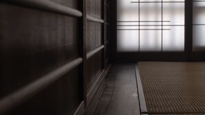 Una habitación japonesa tradicional con suelo de tatami, puertas correderas y pared de madera.