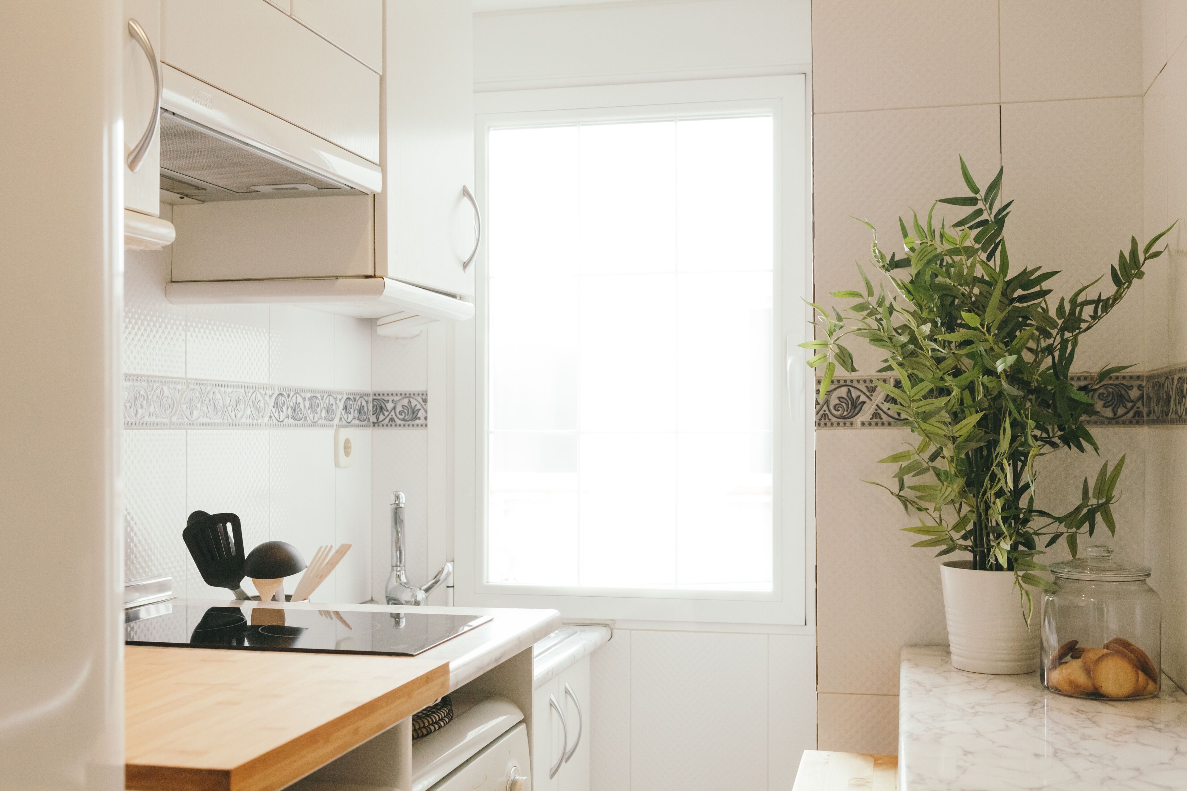 Een moderne keuken met witte kastjes, een houten aanrecht, een spoelbak en een raam.