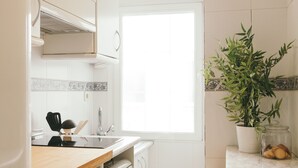Una cocina moderna con armarios blancos, una encimera de madera, un fregadero y una ventana.