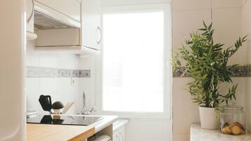 Een moderne keuken met witte kastjes, een houten aanrecht, een spoelbak en een raam.