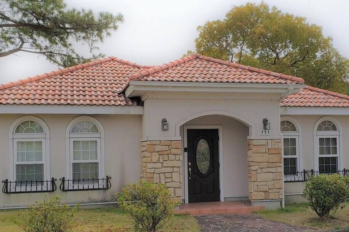 A single-story house with a tiled roof, stone facade, and a black front door.