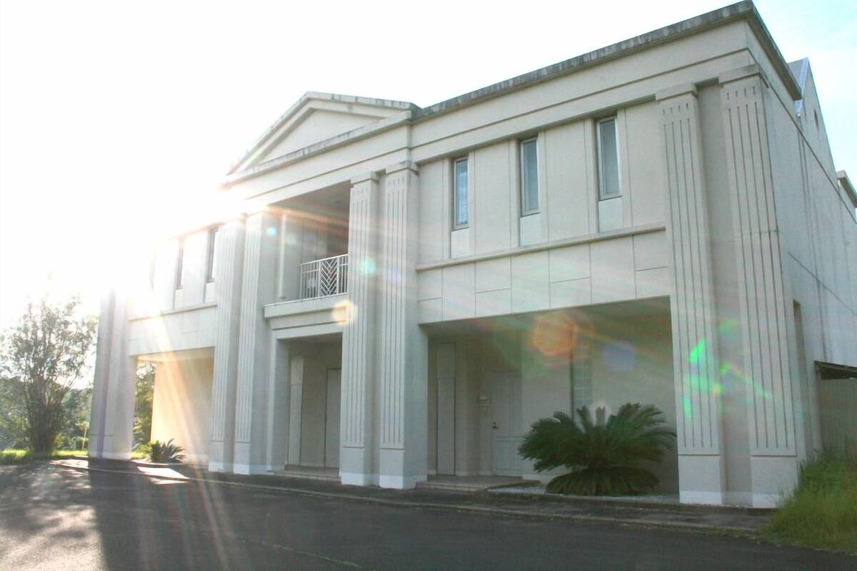 A large, single-story building with a symmetrical facade, large windows, and a central entrance with columns.