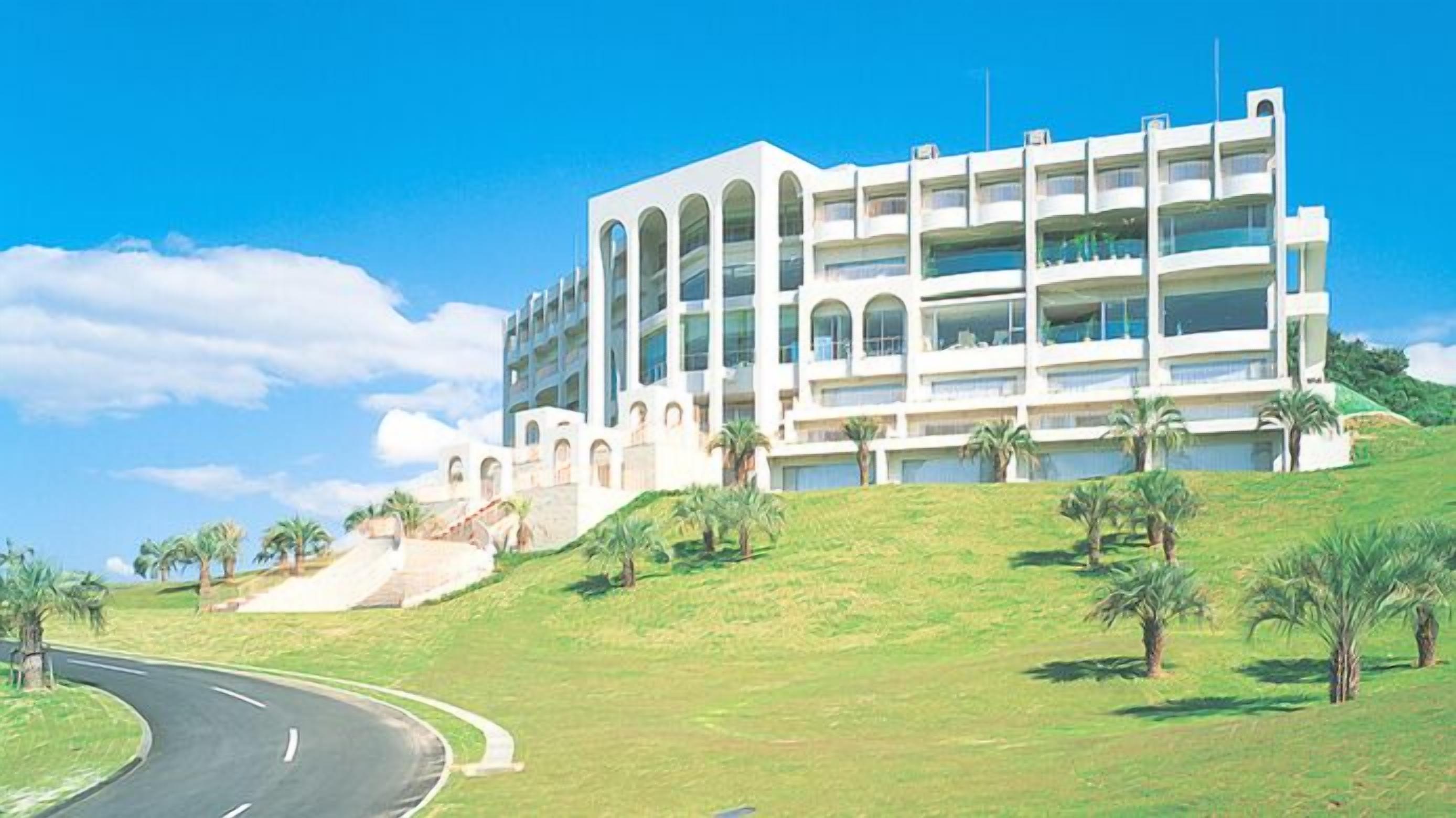 Un hotel de varios pisos con un diseño arquitectónico moderno, que cuenta con balcones y una entrada destacada.