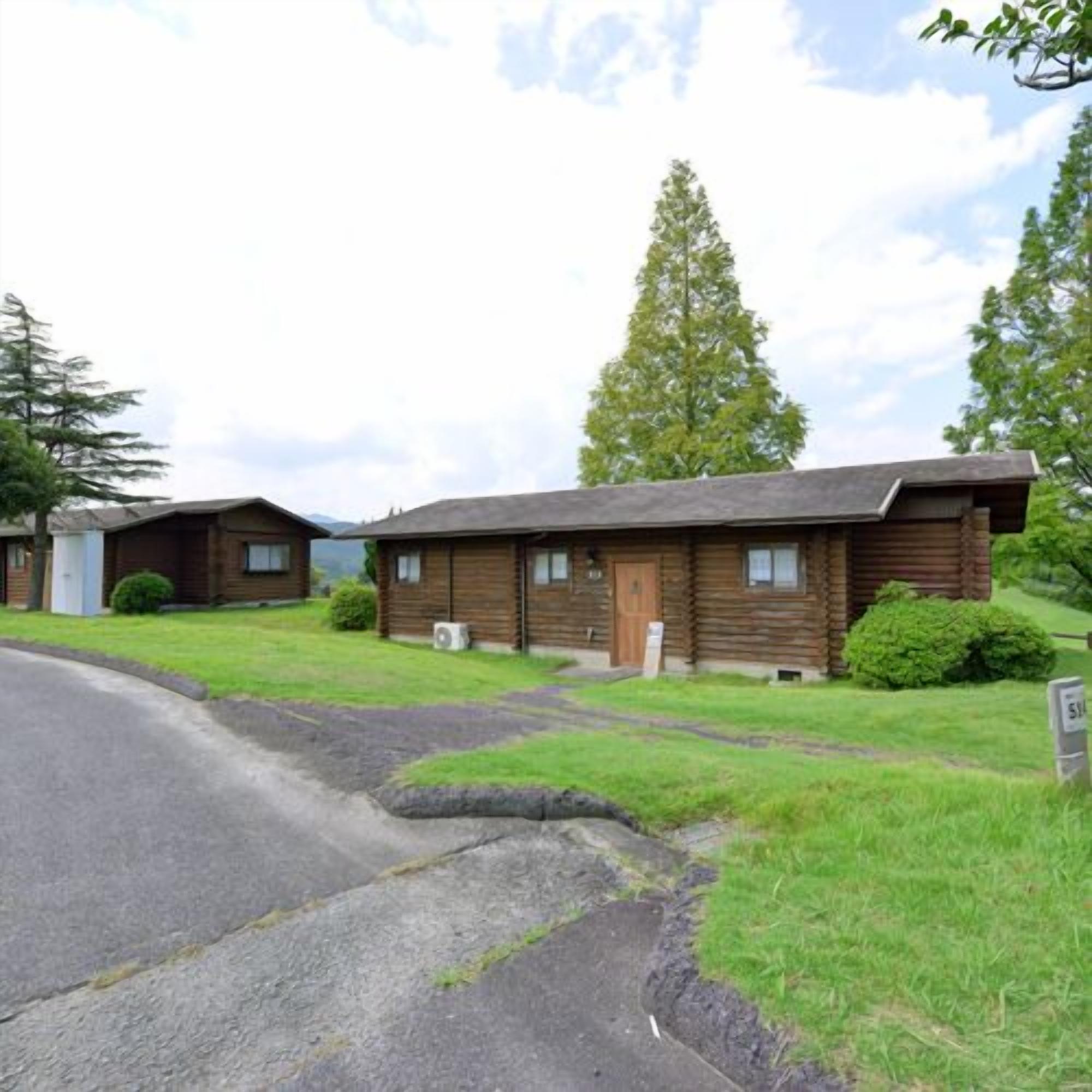 A log cabin-style building with a front porch, a small front yard, and a clear sky.