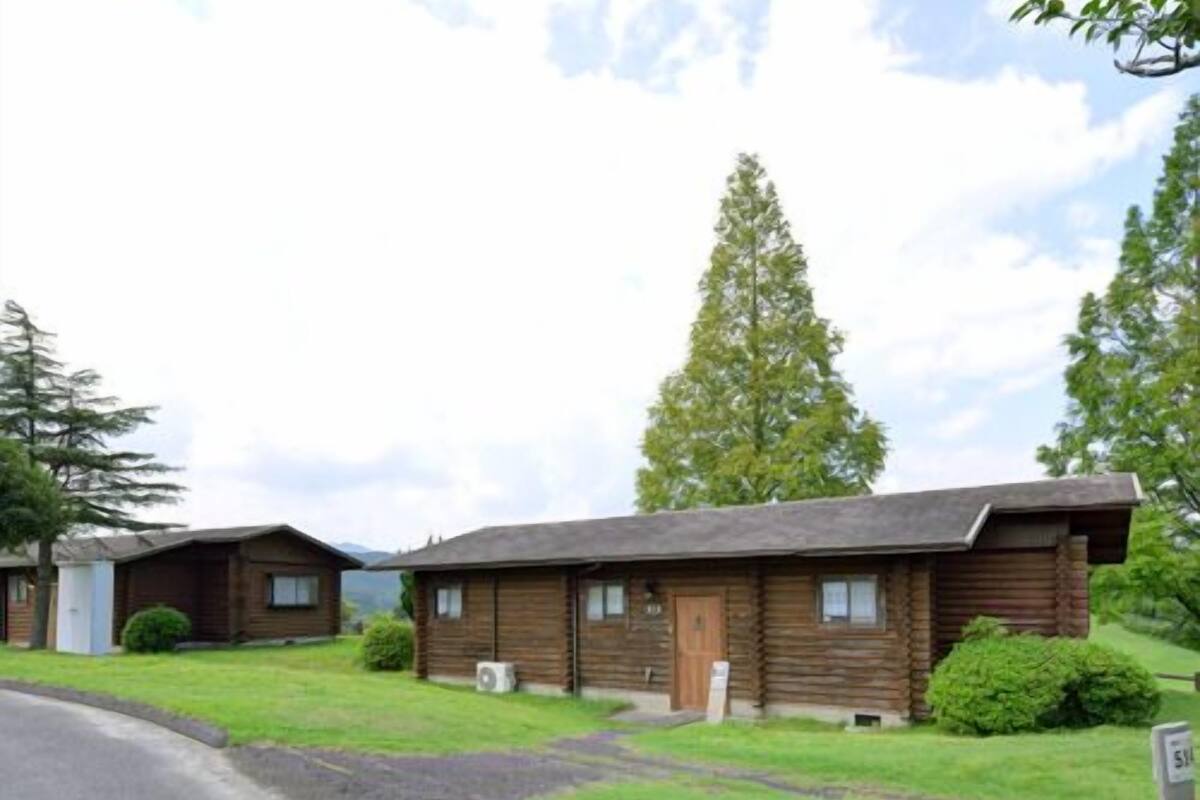 A log cabin-style building with a front porch, a small front yard, and a clear sky.