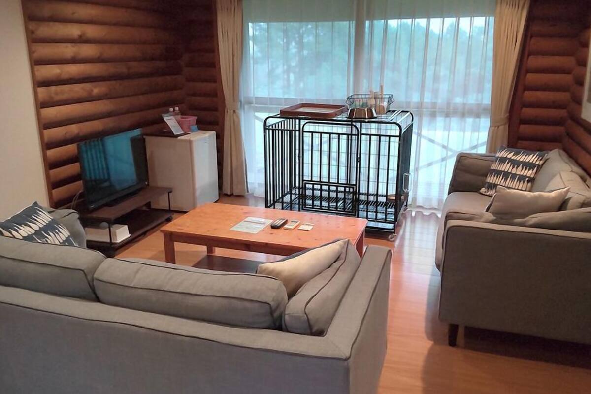 A log cabin interior with a sofa, coffee table, television, and a cage table.