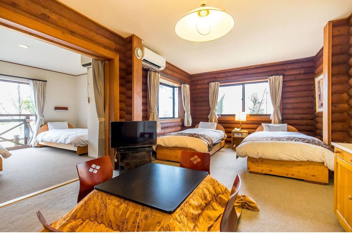 A log cabin-style room with two beds, a TV, a table, and a chair.