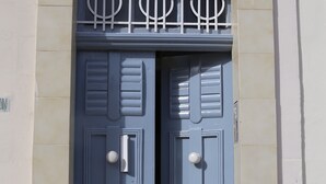 Une porte à deux battants, dotée d’une grille en métal et d’une poignée.