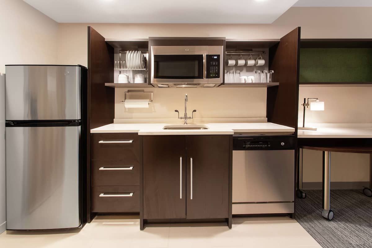 A compact kitchen with a stainless steel refrigerator, a microwave, and a dishwasher.