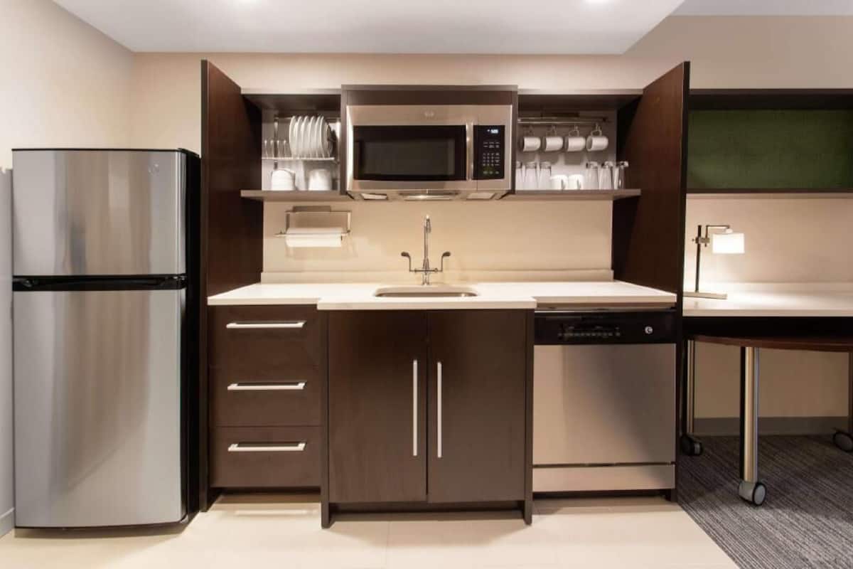 A compact kitchen with a stainless steel refrigerator, a microwave, a dishwasher, and a sink.