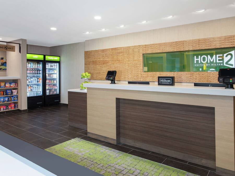 A hotel reception area with a modern design, including a reception desk, a digital kiosk, and a vending machine.