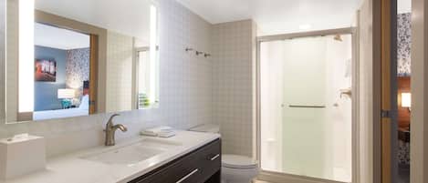 A modern bathroom with a double sink vanity, a toilet, and a glass-enclosed shower area.