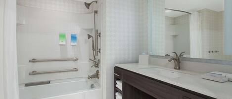 Une salle de bain moderne avec une baignoire, un grand miroir et un meuble-lavabo.
