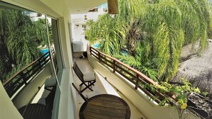 A balcony with a view of a swimming pool, surrounded by lush greenery. - Condo In Downtown of Playa del Carmen, four blocks to the 5th (Playa del Carmen)