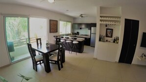 A modern kitchen with a dining area, large windows, and ceiling fans. - Condo In Downtown of Playa del Carmen, four blocks to the 5th (Playa del Carmen)