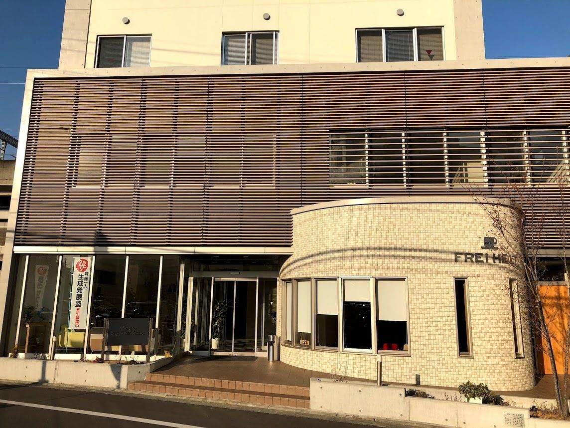 A modern building with a curved corner entrance, large windows, and a sign indicating a business or office space.