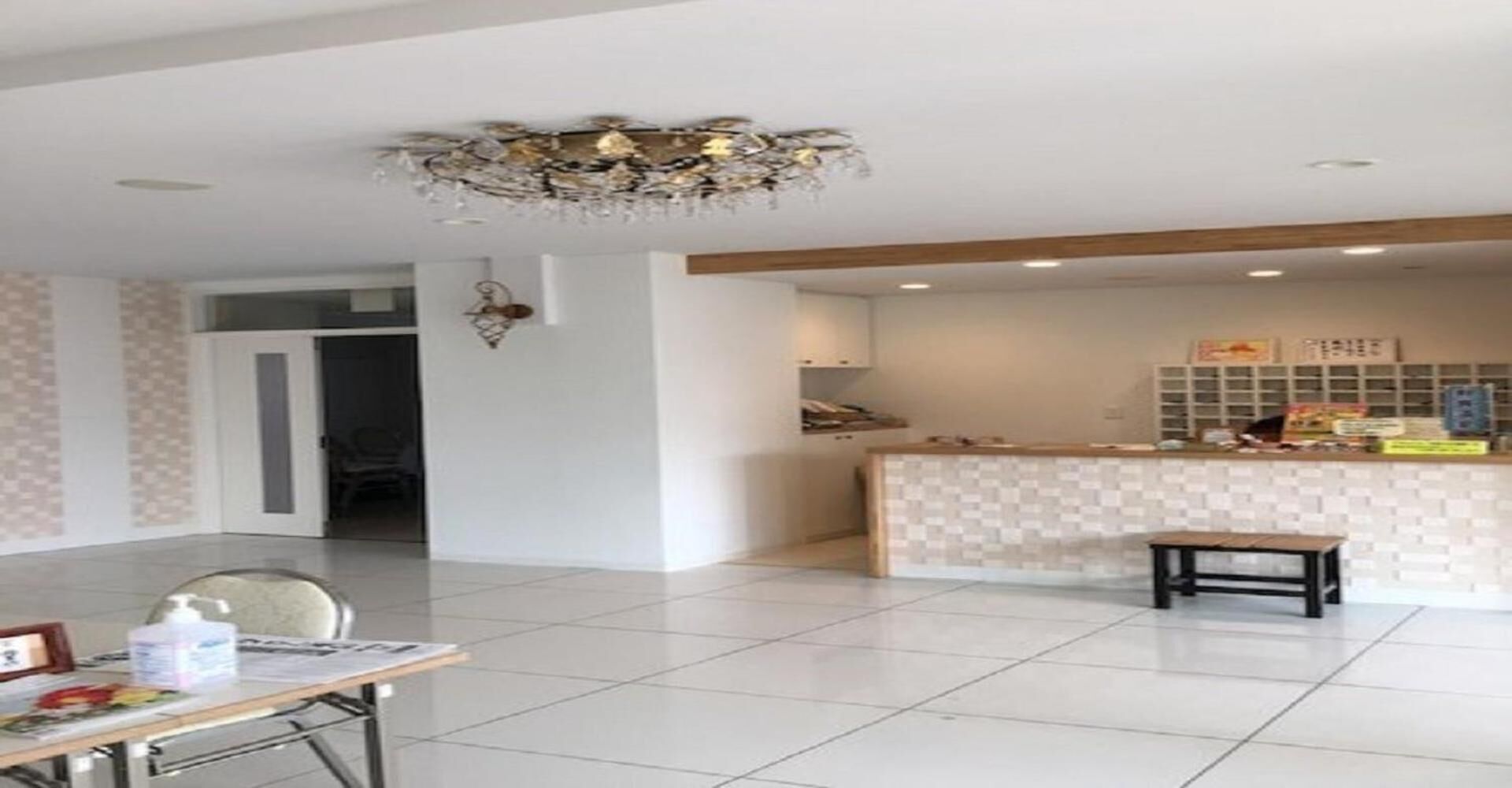 Eine großzügige Hotelhalle mit kariertem Empfangstresen, einer Chandelüster und einem Fliesenboden.