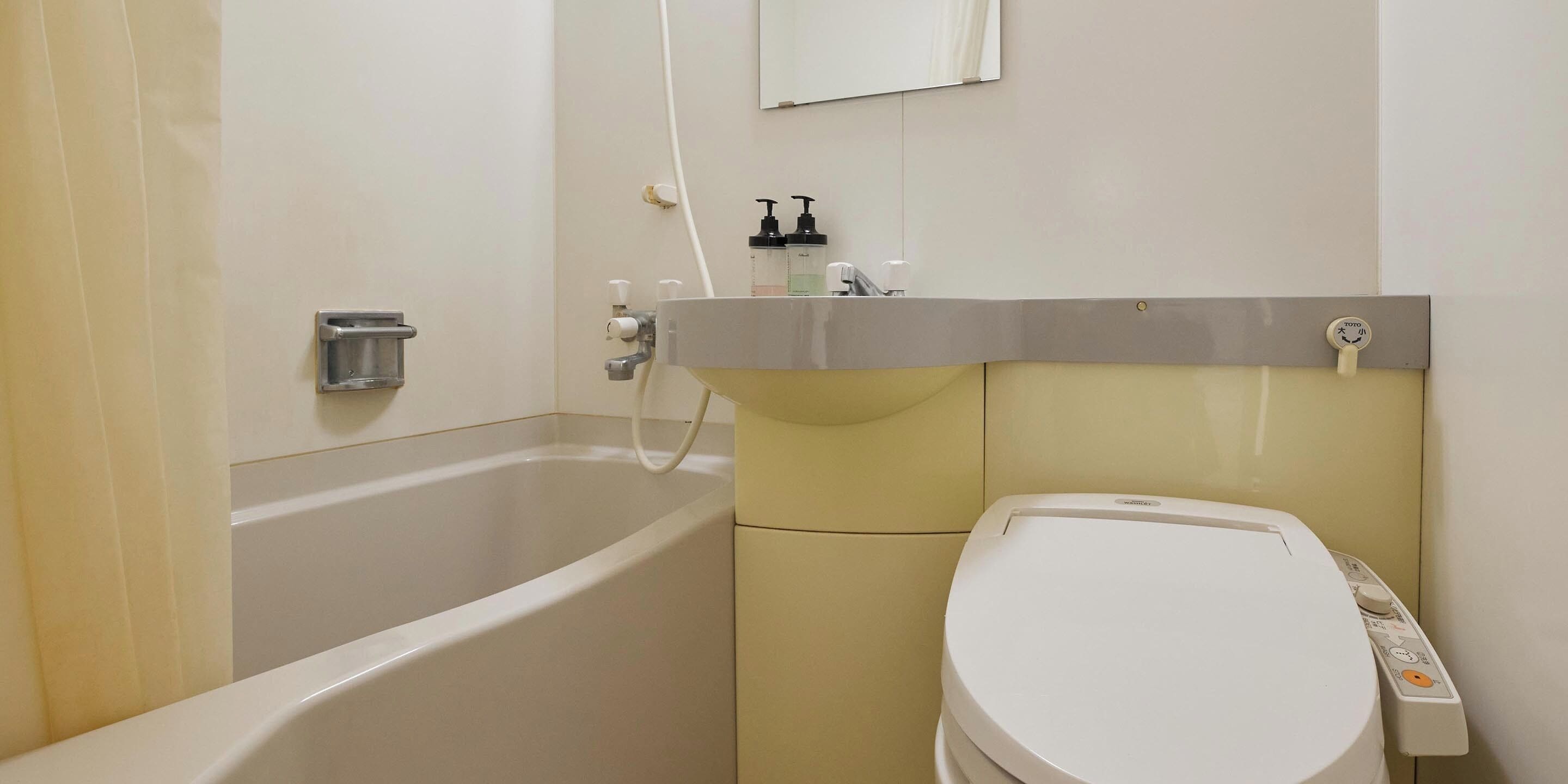 Un baño con bañera, inodoro y un estante con artículos de aseo.