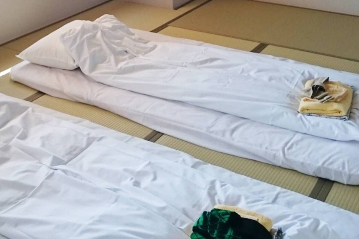A room with tatami mat flooring and two beds with white bedding.