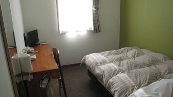Een hotelkamer met een bed, een bureau met een computer en een raam met gordijnen.